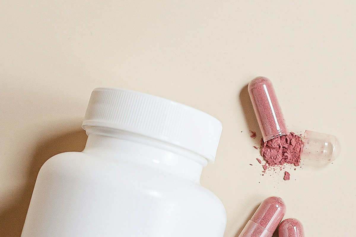 white bottle container with reddish powder from capsule