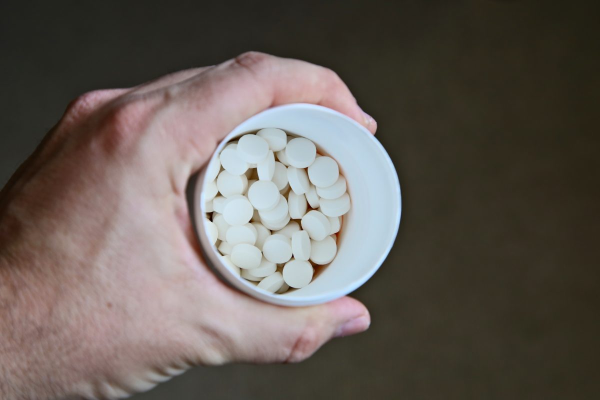 close up shot of a man holding container of white tablets