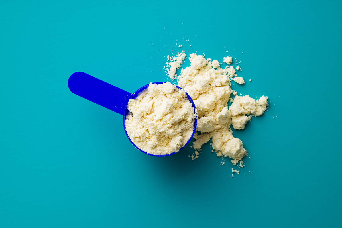 closeup shot of creamy white powder in blue scoop and blue background