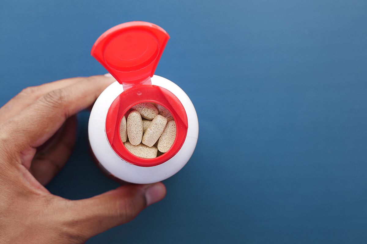 close up shot of capsules inside white supplement bottle with red lid