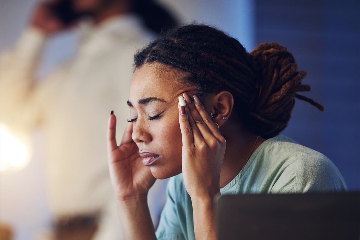 stressed woman eyes closed rubbing side of head