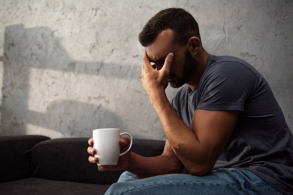 man holding cup of coffee while being stressed out