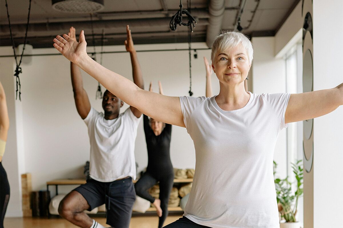 elderly woman in a yoga class wearing white shirt