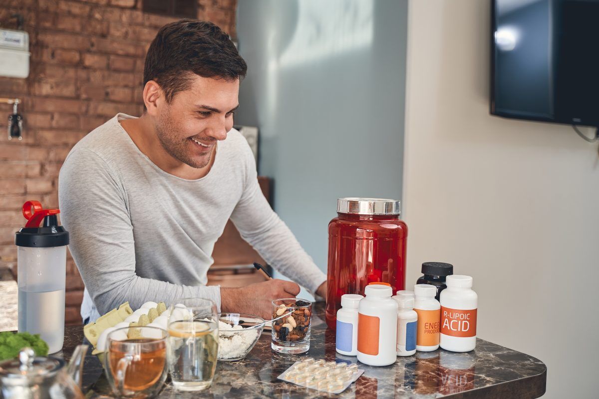 man looking at different supplement bottles on marble counter