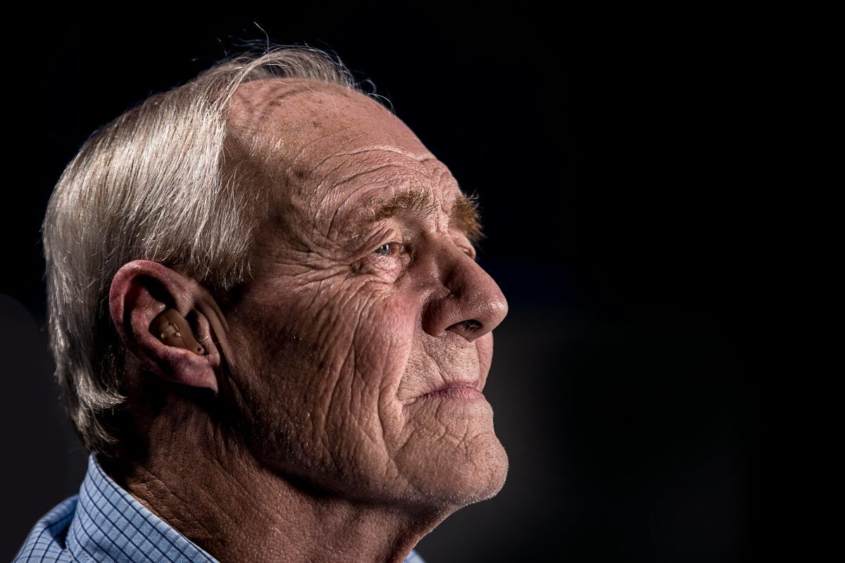 elderly man looking far ahead wearing a hearing aid